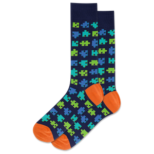Navy sock with green and blue puzzle piece pattern and orange toes and heels on a white background