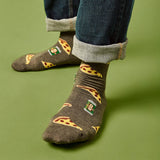 Person wearing socks with pizza slice and beer can designs on a green background