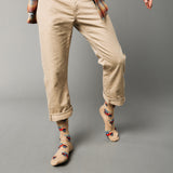 Person wearing beige pants and patterned socks with cars and surf boards on a gray background