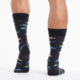 Black socks with colorful fish pattern worn by a person on a white background