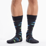 Black socks with colorful fish pattern worn by a person on a white background