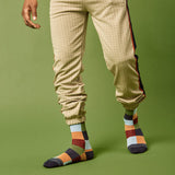 Person wearing beige checkered pants and multicolored socks on a green background thumbnail