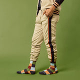 Person wearing checkered pants with side stripes and colorful socks on a green background