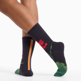 Black socks with floral designs worn by a person on a white background