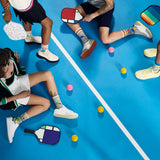 People playing with colorful pickleball paddles and balls on a blue court. thumbnail
