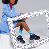 Woman in a blue outfit with matching socks and shoes sitting inside a decorative frame.
