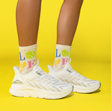 White sneakers and socks with colorful letters on a yellow background thumbnail