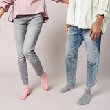 Two people wearing jeans and socks on a plain background