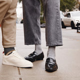Two pairs of feet wearing different shoes on a sidewalk.