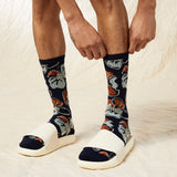 Person wearing navy socks with fox pattern and white sandals on a light background