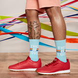 Person wearing light blue socks with 'This is Love' text and rainbow colors, red sneakers, on a colorful abstract background. thumbnail