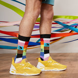 Person wearing colorful socks with a pattern and yellow sneakers on a wooden floor.