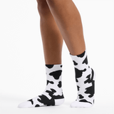 Cow print socks worn by a person on a white background