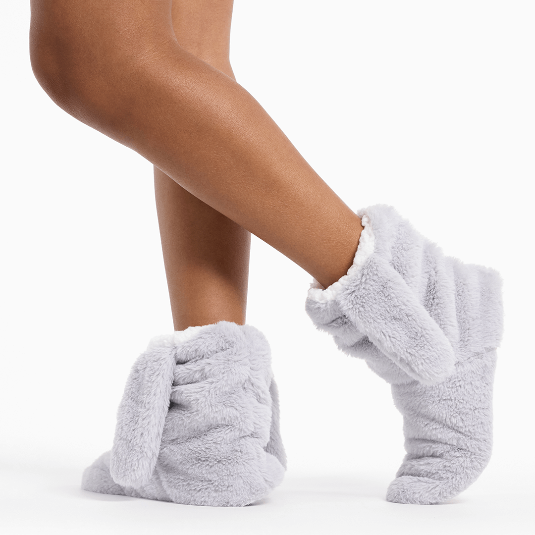 Gray fuzzy socks worn by a person on a white background