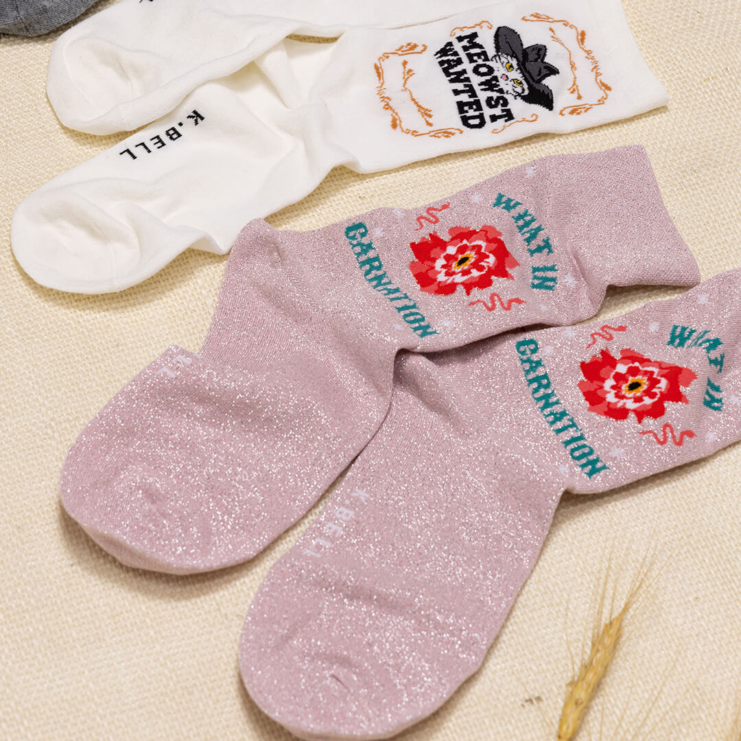 Pink socks with floral designs and text on a beige surface
