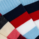 Close-up of multicolored socks with red, blue, black, and beige stripes.