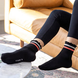 Person wearing black socks with striped cuffs in a living room setting thumbnail