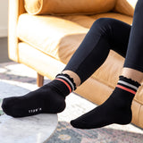 Person wearing black socks with striped cuffs in a living room setting