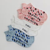 Set of K. Bell socks in pink, white, and blue with black pattern on a light gray background
