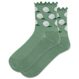 A pair of green crew socks with a lettuce edge design and white golf ball patterns, displayed on a piece of grass next to a golf club and two golf balls.